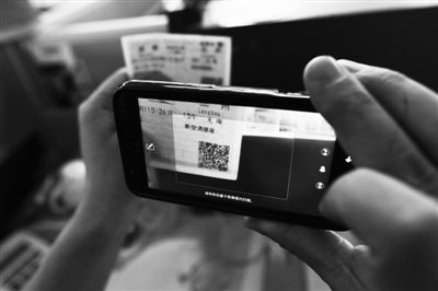 昨日，一位乘客用手机扫描自己的火车票信息。通过扫描软件可获得火车票二维码含有的身份证信息。 本报记者 浦峰 摄